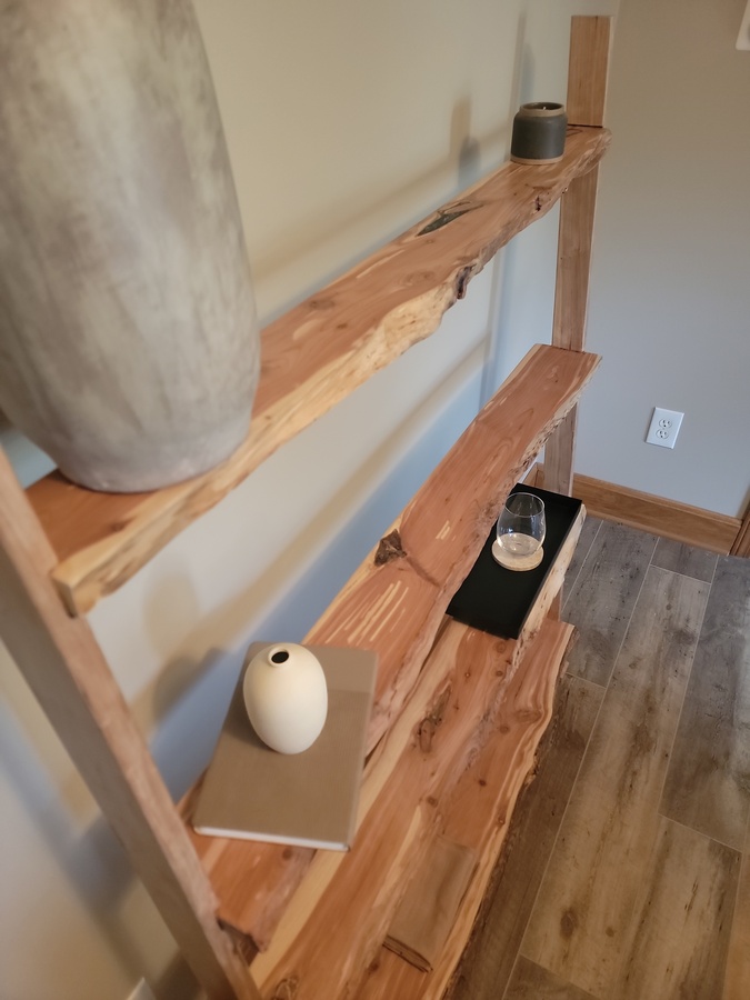 View along the four level cedar shelves showing books, vessels, and a tray